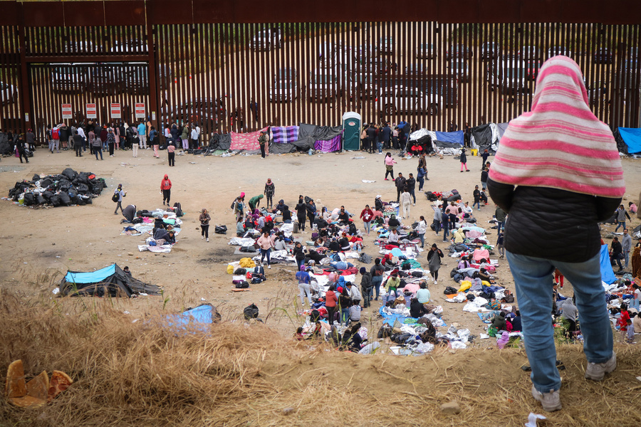Una mujer mirando el campamento instalado entre los muros fronterizos que separan San Diego de Tijuana, México. (Sara Salazar IOM 2023)